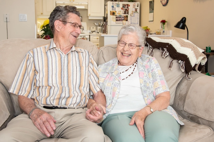 Two residents enjoying time together on a couch.