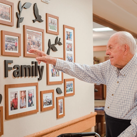 Resident admiring family photos on a wall.