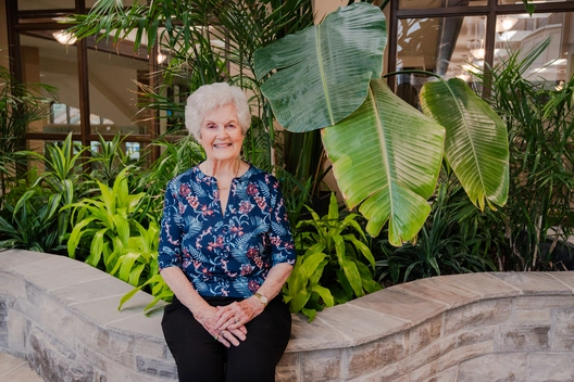 Resident sitting amidst lush indoor plants