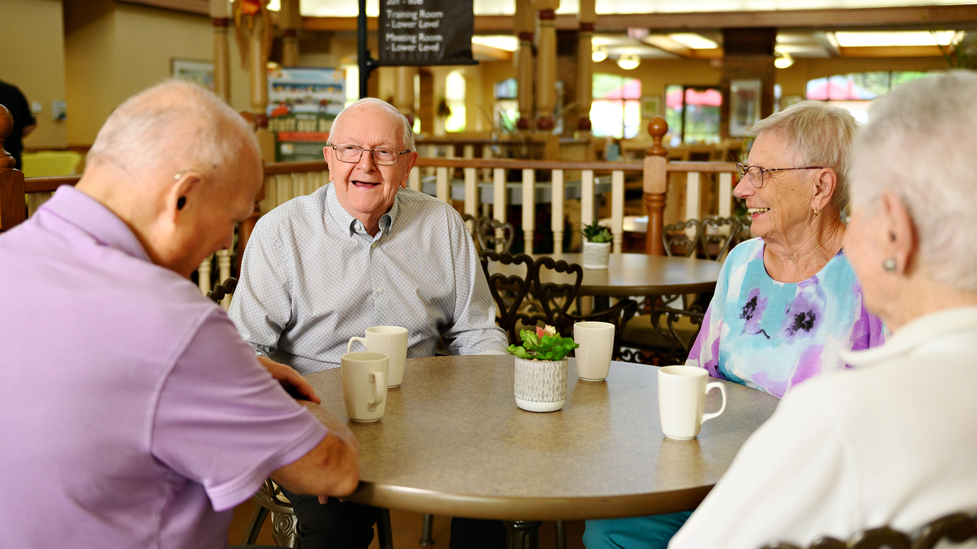 Residents enjoying conversation around a table.