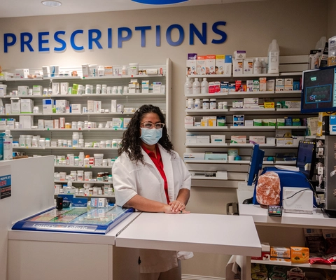 Pharmacy staff member at a prescription counter.