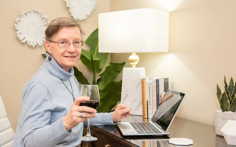 Senior woman enjoying a drink at her desk.