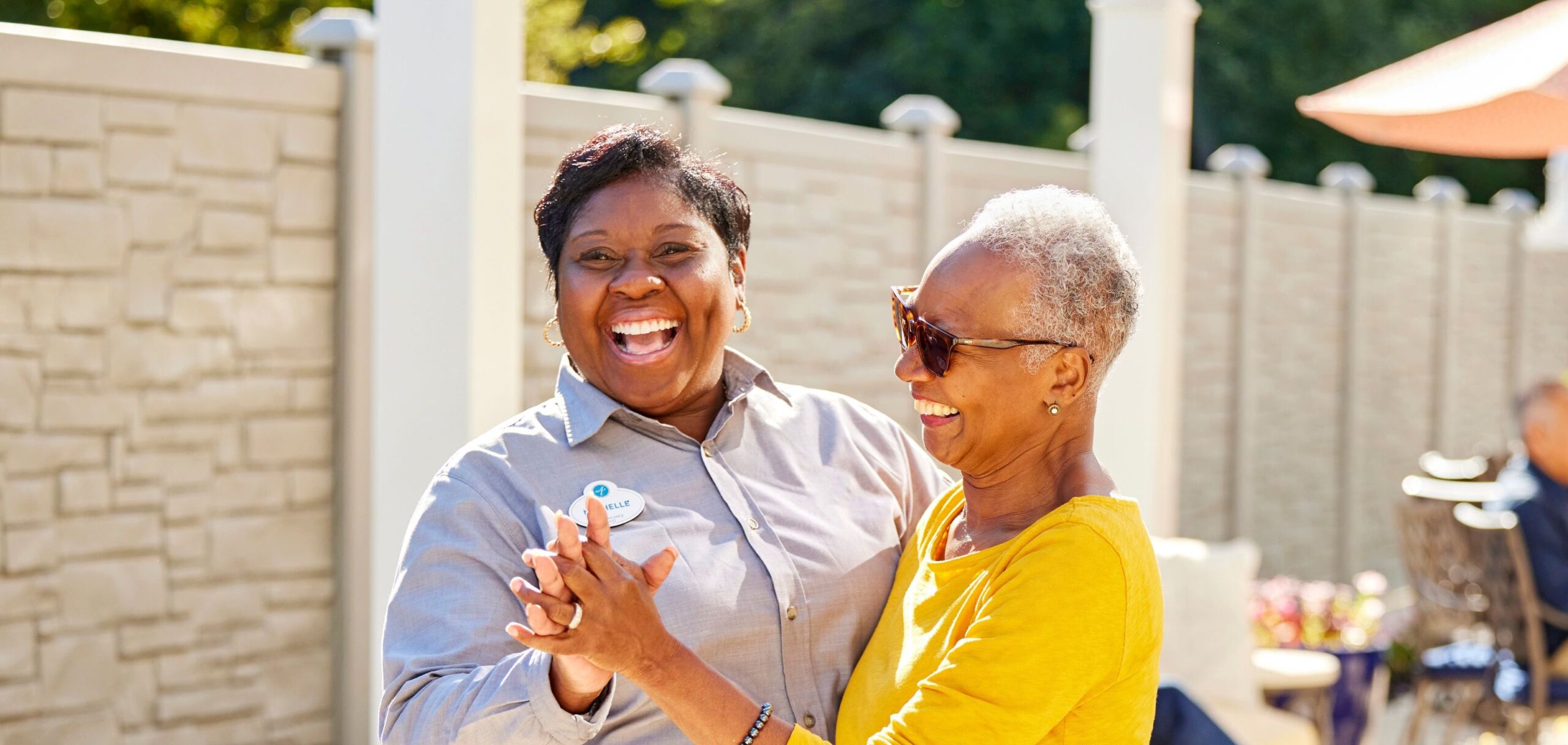 Staff and resident joyfully dancing outdoors