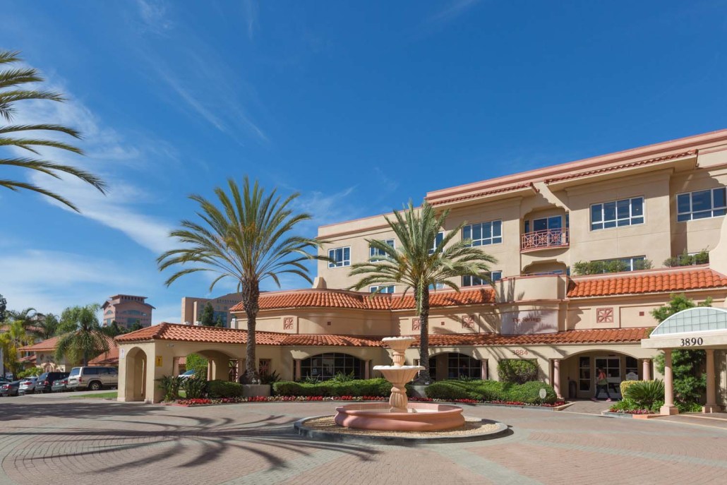 Exterior view of The Springs of Pacific Regent with palm trees.