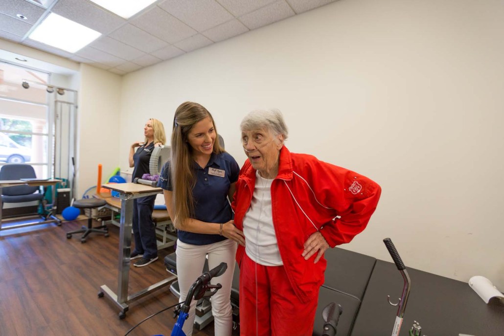 Staff assisting an elderly resident in a therapy setting.