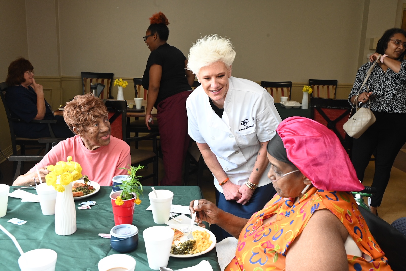 Residents enjoying a meal with staff interaction.