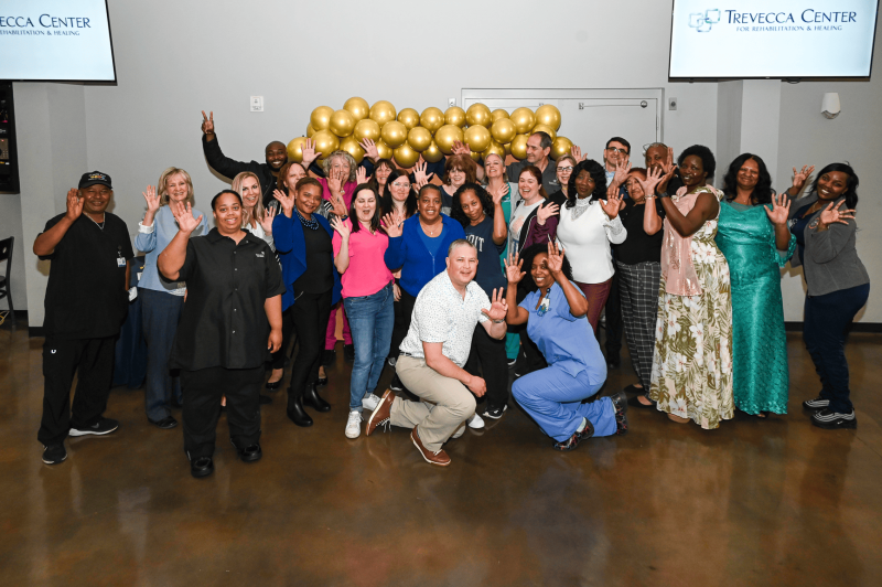 Group photo of staff and residents celebrating together.