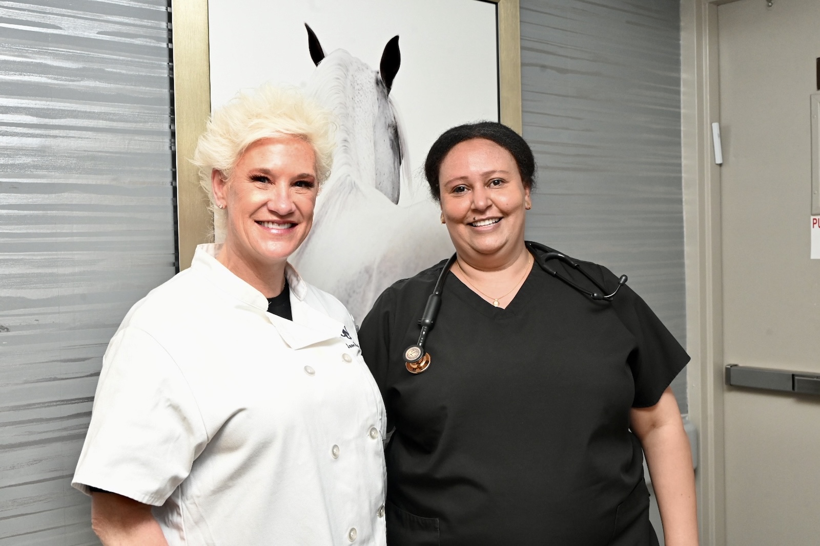 Two staff members smiling in a hallway.