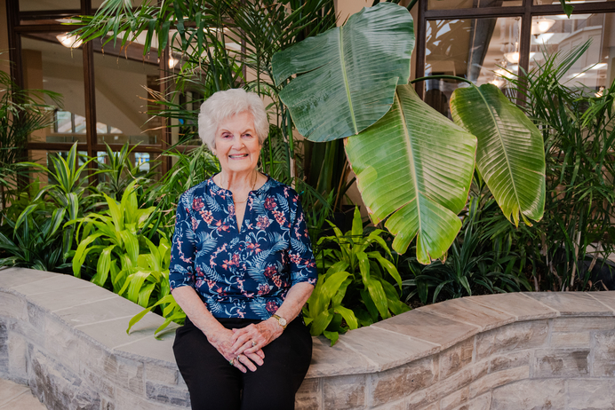 Senior woman smiling in lush indoor greenery