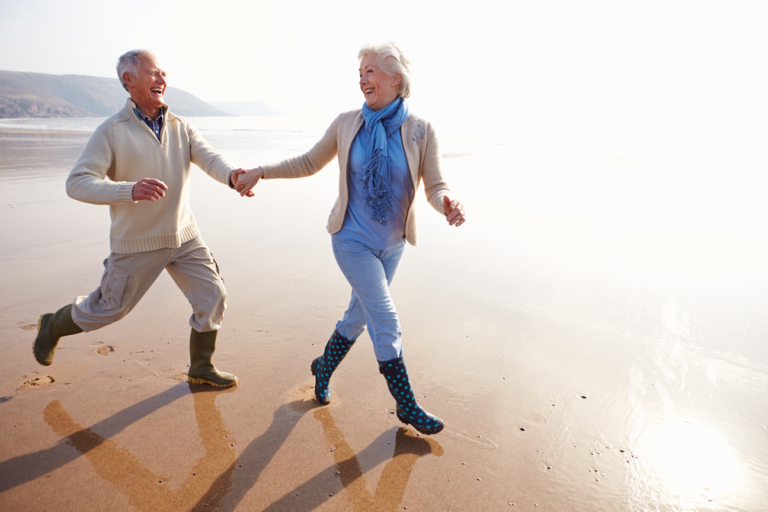Elderly couple walking hand in hand on the beach