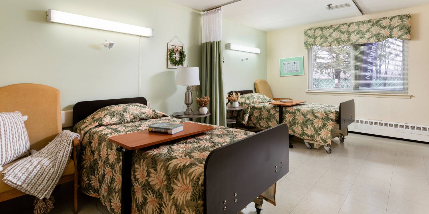 Shared resident room with floral bedding and natural light