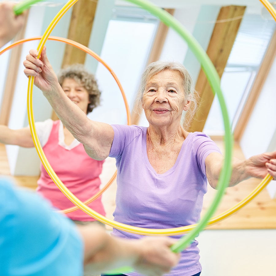 Seniors participating in a hula hoop exercise class.