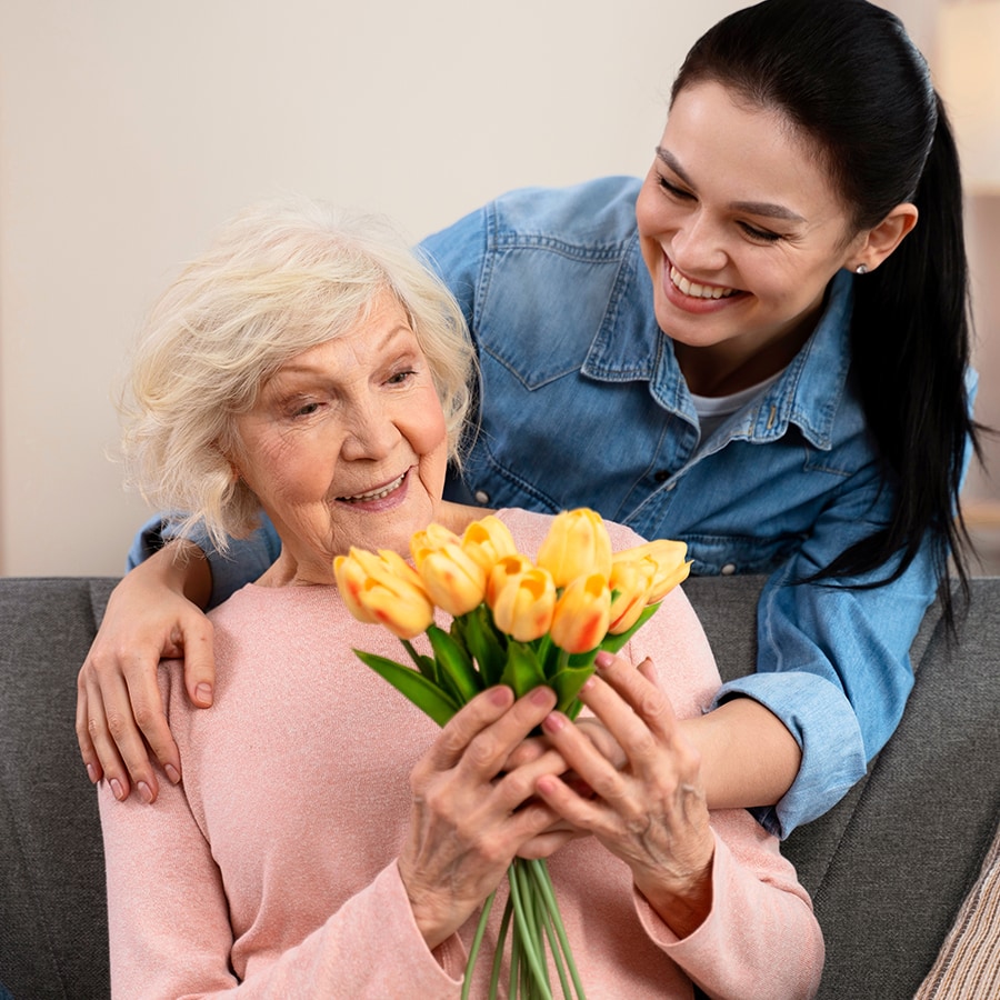 Senior resident receiving flowers from a caregiver