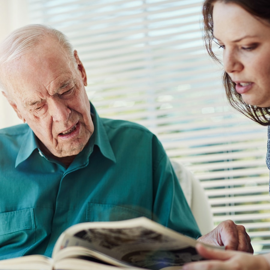 Elderly man and caregiver reading together
