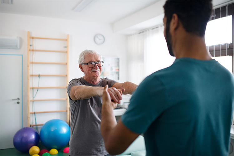 Senior man engaging in physical therapy with staff member.