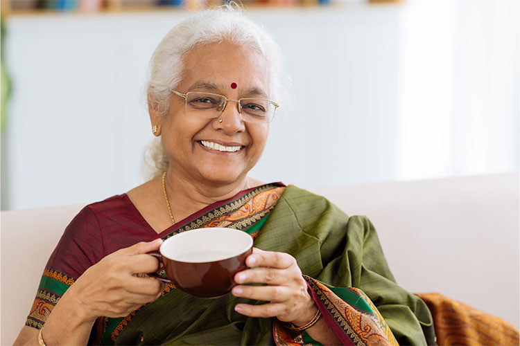 Senior woman enjoying a cup of tea in a cozy setting.