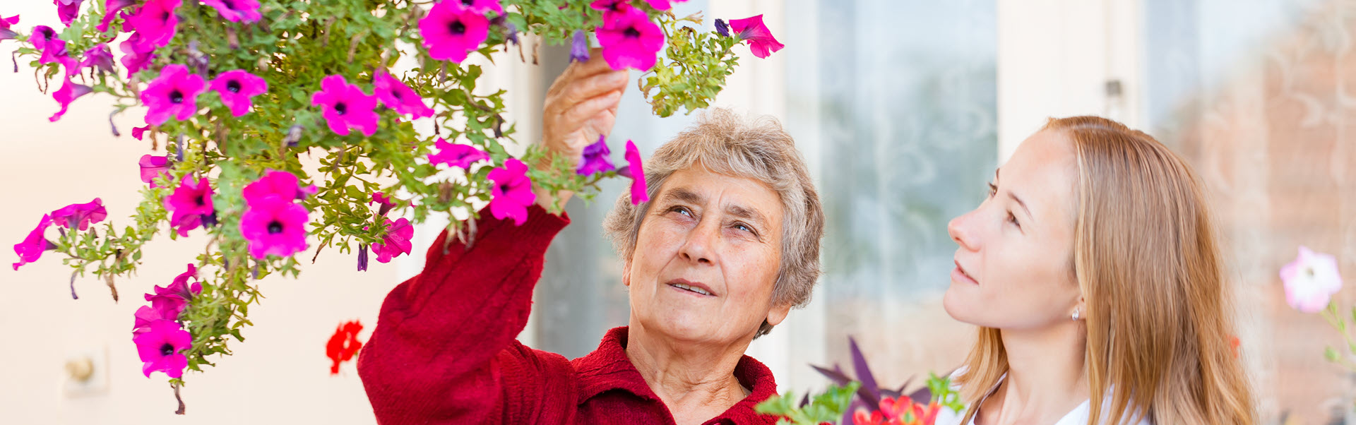 A caregiver and resident enjoying flowers together.
