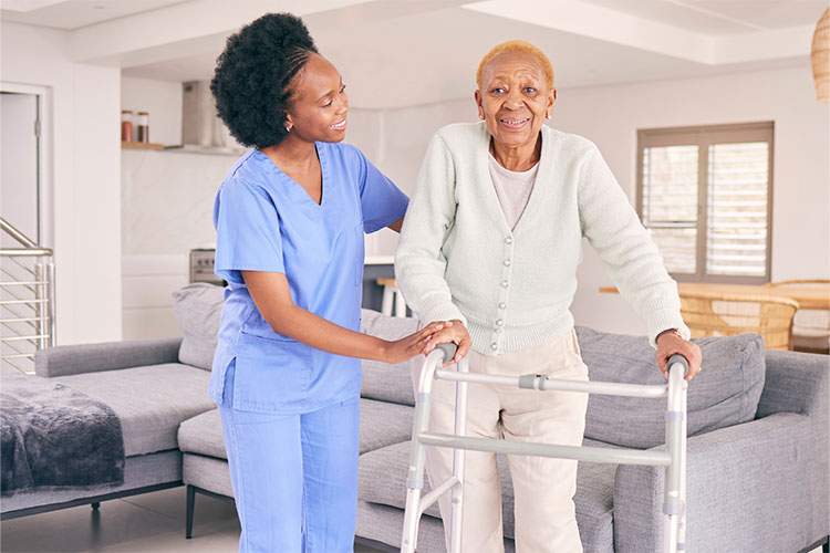 Staff assisting a resident with a walker in a living area.