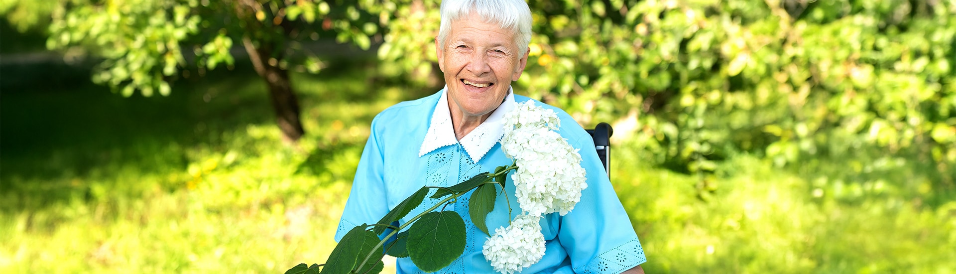 Senior woman smiling in a garden setting.