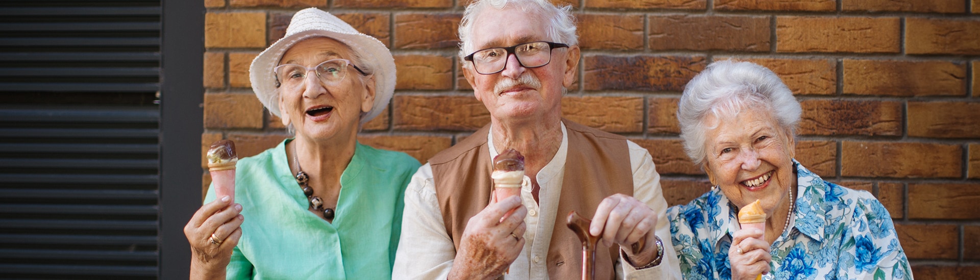 Seniors happily enjoying ice cream outdoors.