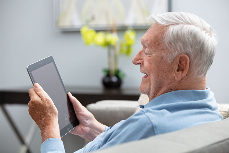 Elderly man enjoying a tablet in a cozy living space.