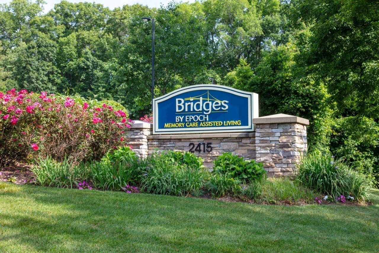 Sign for Bridges by Epoch at Trumbull surrounded by flowers.