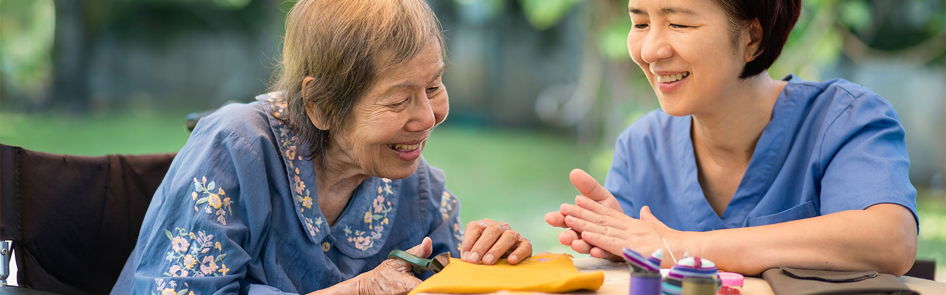 Elderly woman and caregiver engaging in an activity outdoors.