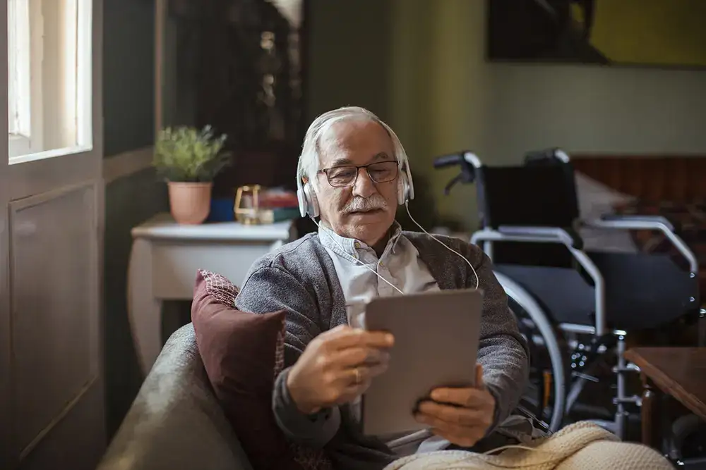 Senior man using a tablet in a cozy space.