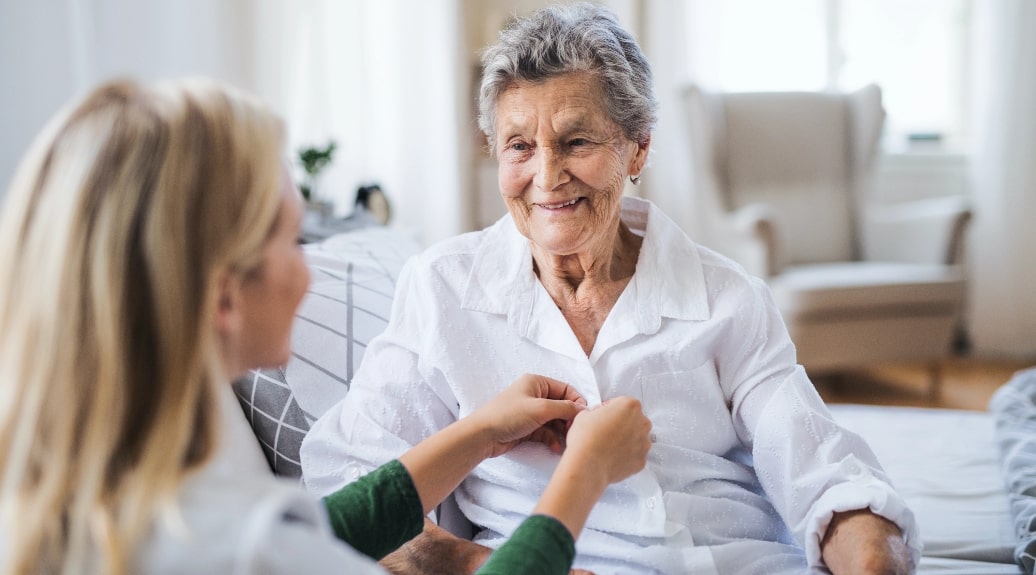 Senior woman smiling with caregiver in living room