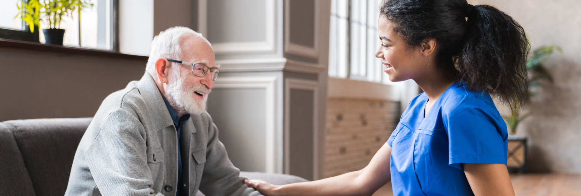 Elderly man conversing with caregiver in a common area.