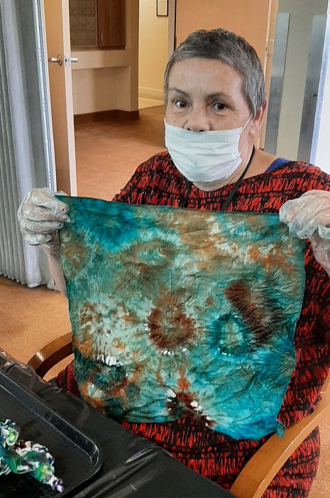 Resident showcasing a dyed fabric piece during an activity.