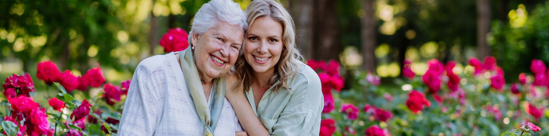 Smiling resident with family in a rose garden.