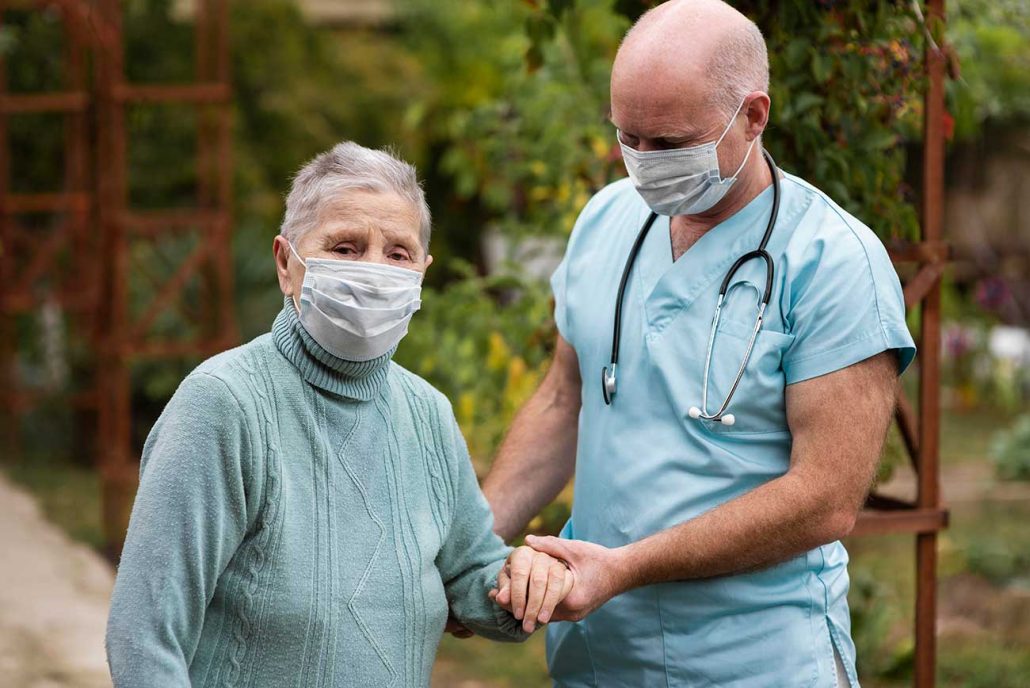 Healthcare worker assisting a senior woman outdoors.