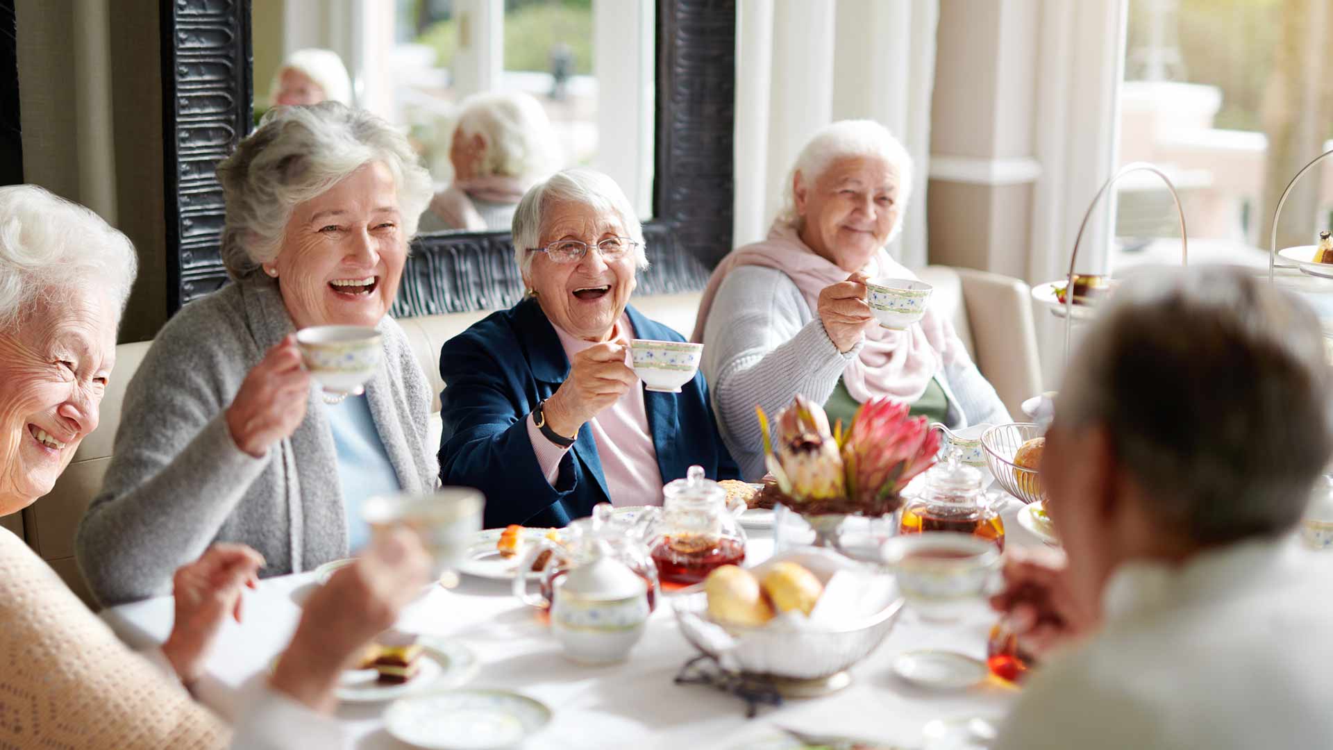 Seniors enjoying tea in a communal dining space.
