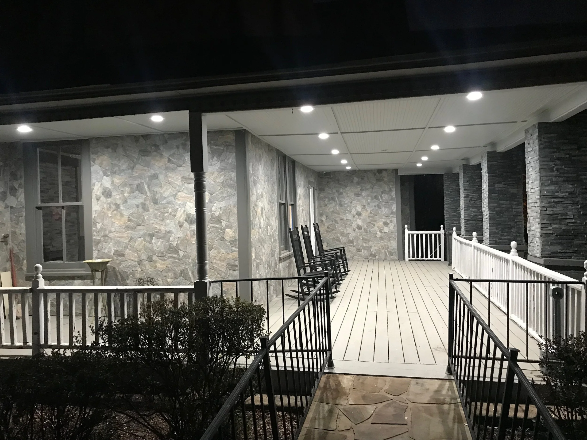 Covered porch area with rocking chairs at night