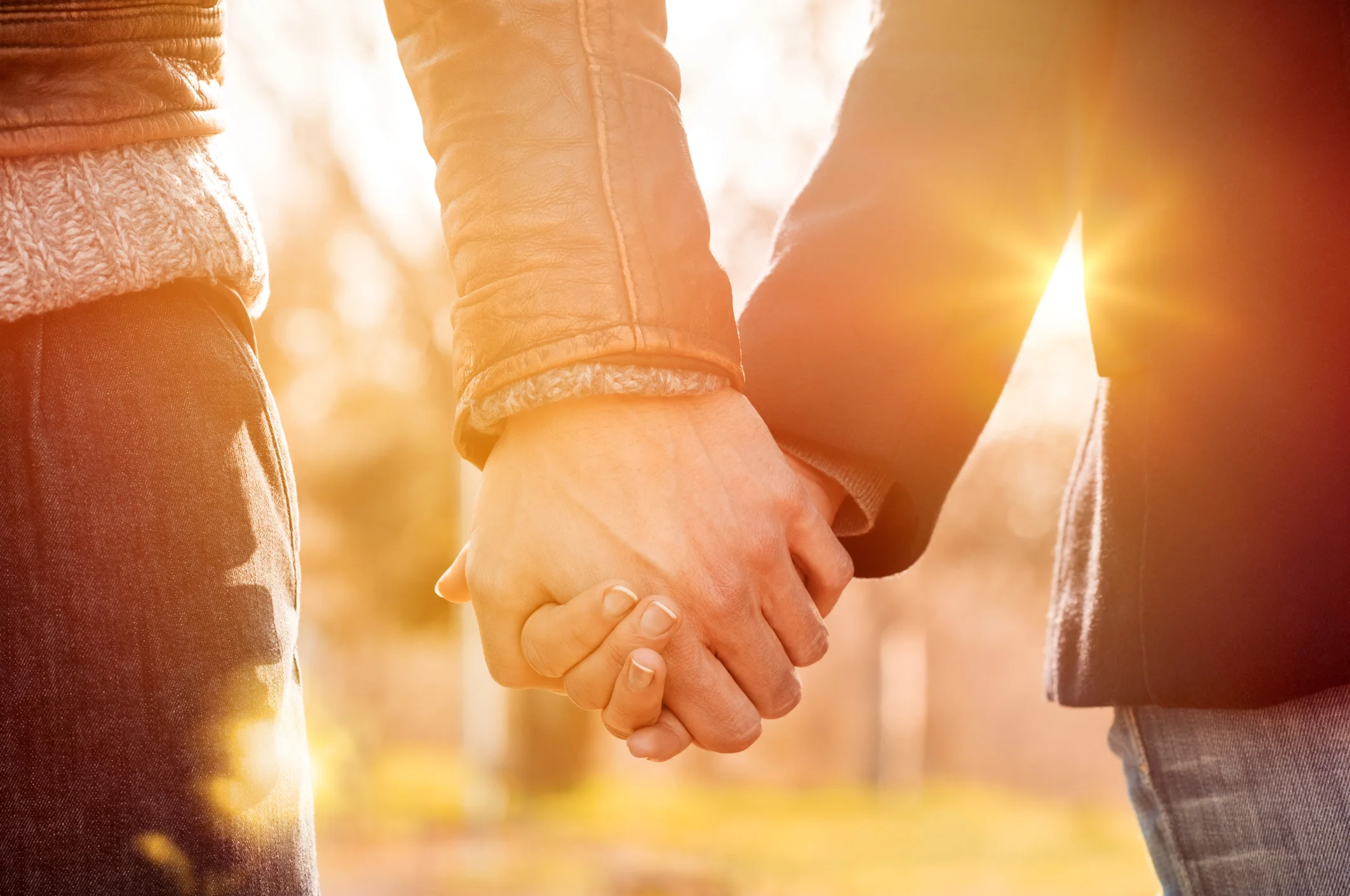Two hands holding in an outdoor setting.
