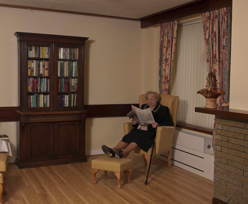 Elderly woman reading a newspaper in a cozy area