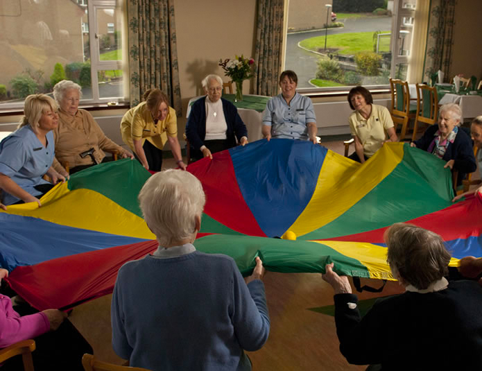 Residents enjoying a colorful activity with staff assistance.