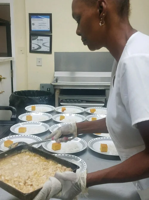 Staff member serving meals in the dining area.