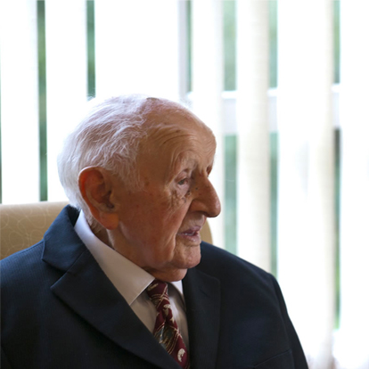 A senior resident seated indoors, smiling.