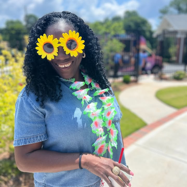 Smiling woman wearing flower sunglasses outdoors.