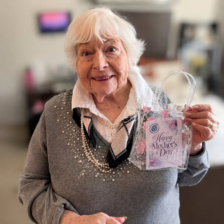 Elderly woman celebrating Mother's Day with a gift bag.