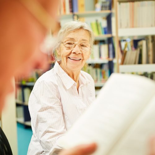 Senior woman smiling while reading a book.