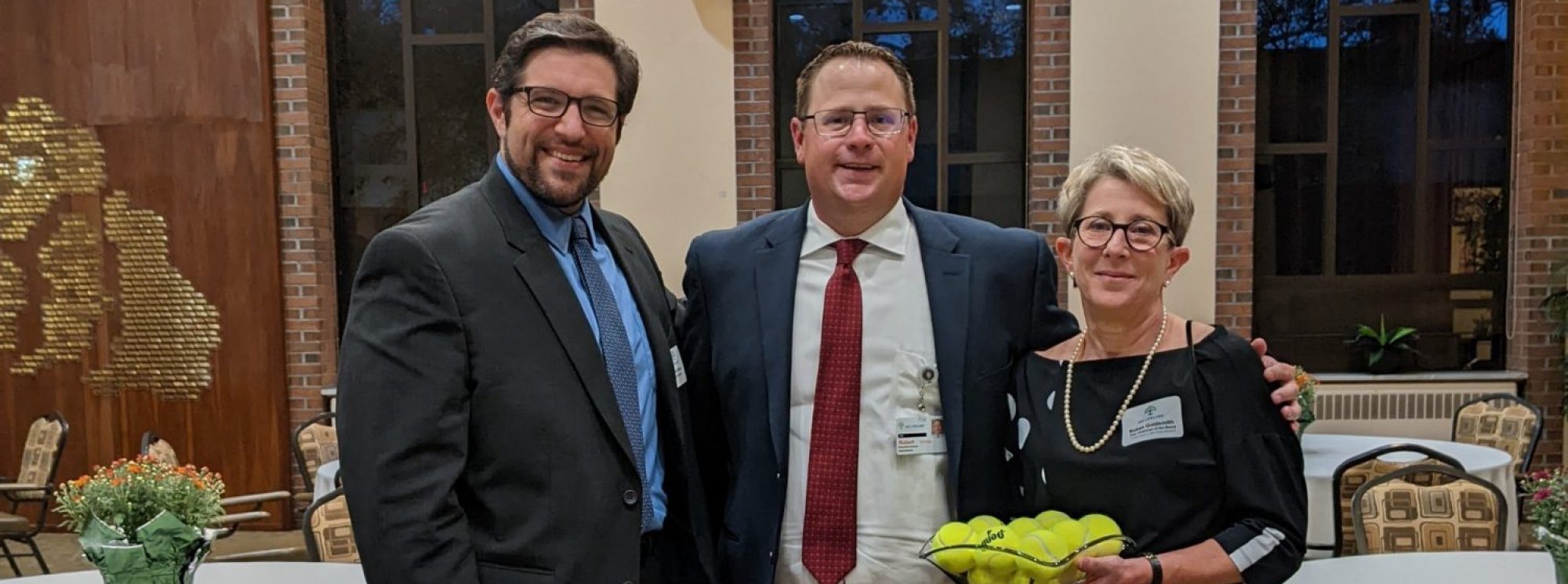 Three people smiling in a social area with decor.