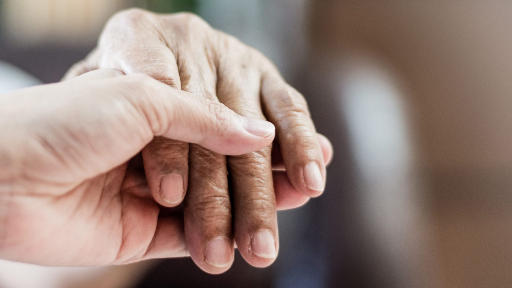Two hands holding in a caring gesture.