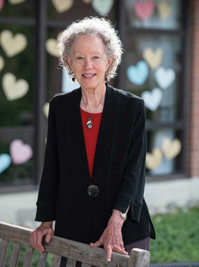 Smiling woman with curly hair in front of heart decorations.