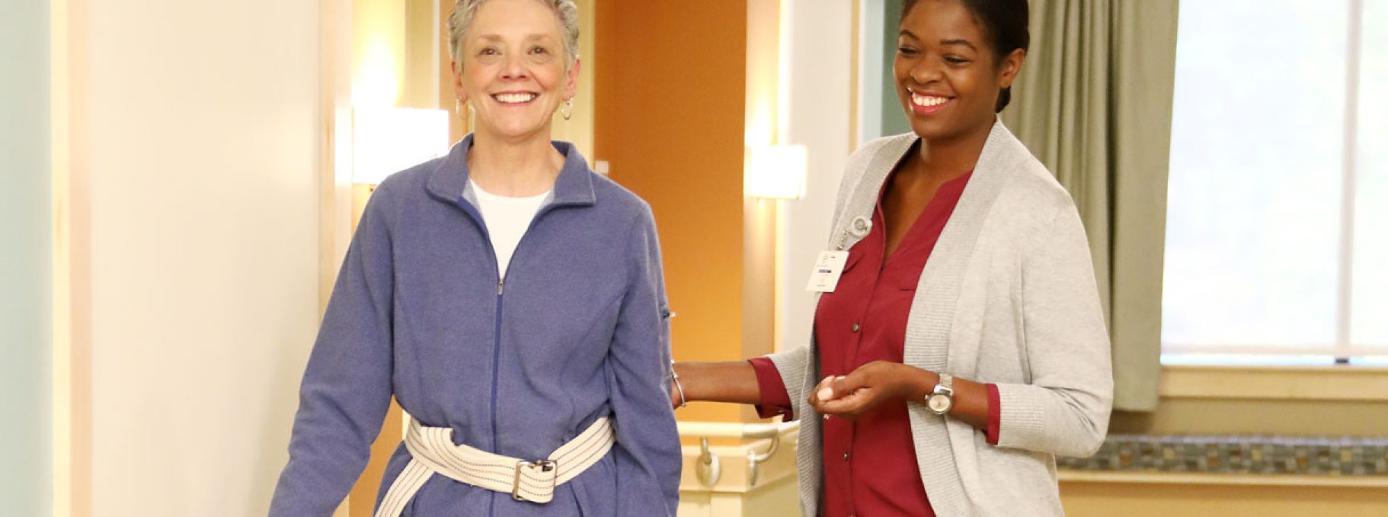 Resident smiling while walking with staff member