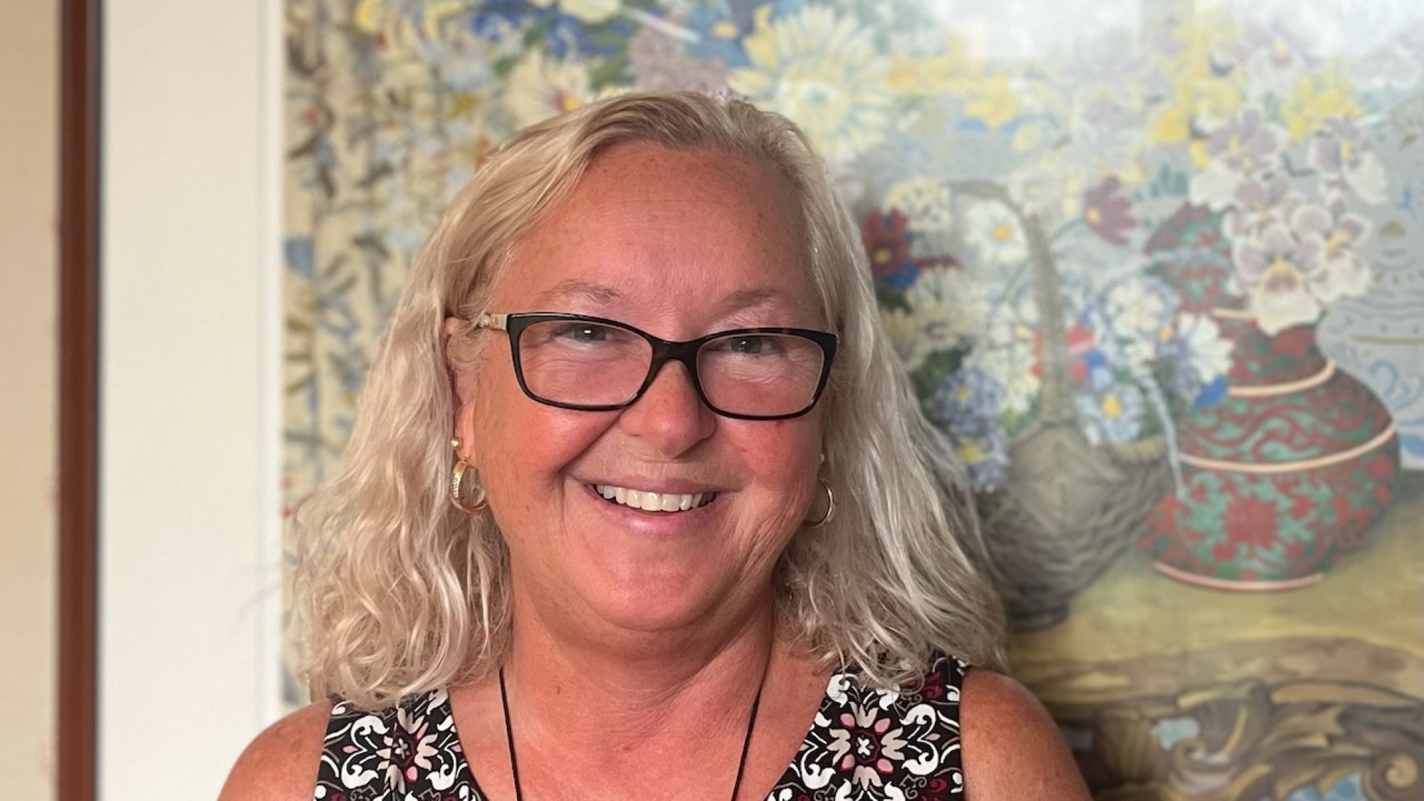 Smiling staff member with a floral background