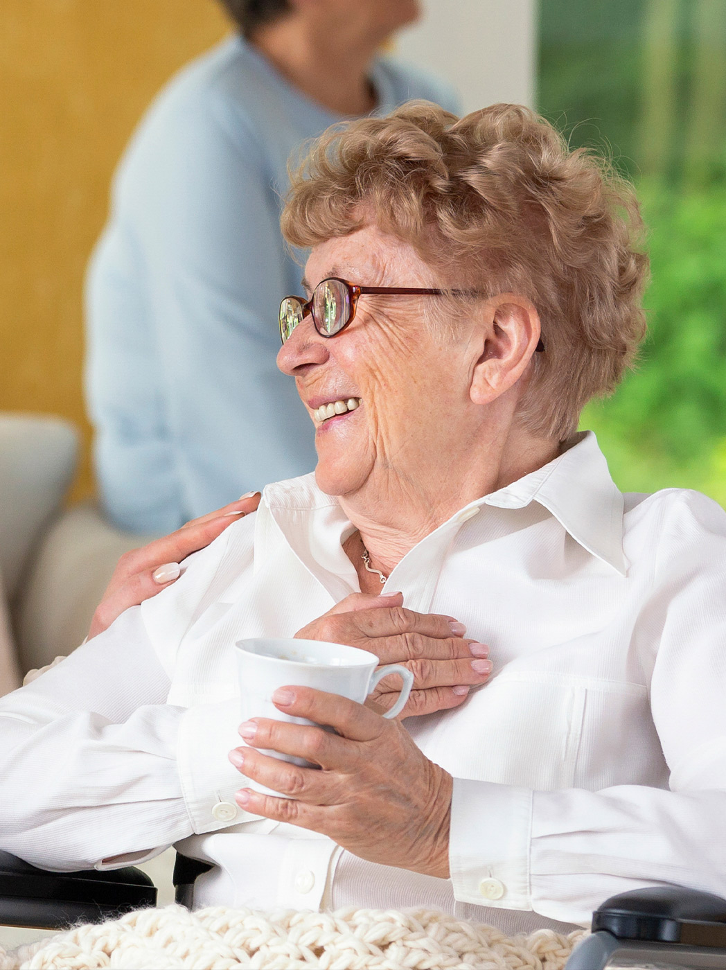 Smiling elderly woman enjoying a conversation indoors.