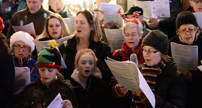 A group of people singing with sheet music.